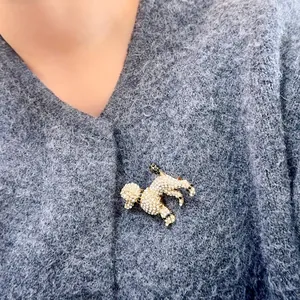 Vue détaillée de la broche caniche en strass brillants sur un cardigan en maille grise