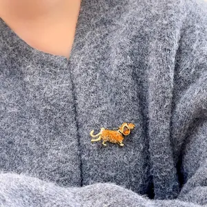 Détail d'une broche teckel avec cristaux épinglée sur un pull en laine gris