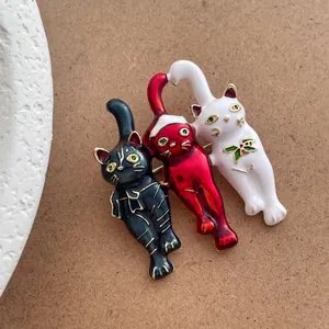 Macro shot of three colorful cat brooches with festive Christmas elements and oil-drop finish