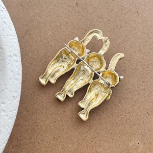 Detail view of the metal brooch back featuring three cat outlines and a secure safety pin