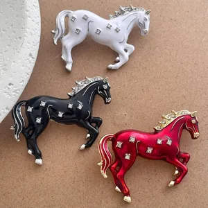 Détail de broches de cheval au galop en blanc, noir et rouge avec des strass brillants