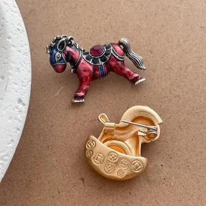 Detail of vintage horse brooches featuring red enamel coating and golden metal coin pattern