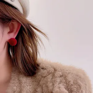 Close-up of elegant red flocked ball stud earrings worn with a cozy winter outfit