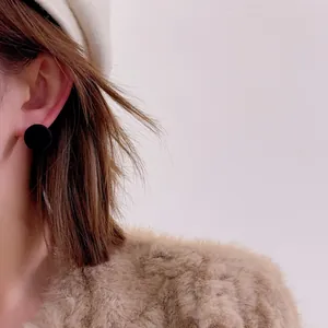 Detail of elegant wine red flocked ball earrings worn by model for autumn winter style