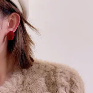 Detail of red flocked irregular round stud earrings paired with autumn winter outfit
