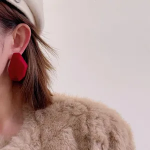 Macro shot of red geometric flocked earrings on a model for a stylish autumn look