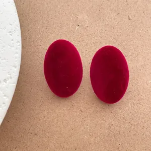 Close-up of elegant burgundy flocked oval stud earrings with fine velvet texture