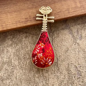 Elegante broche pipa chino con borde de metal dorado y bordado floral de seda roja