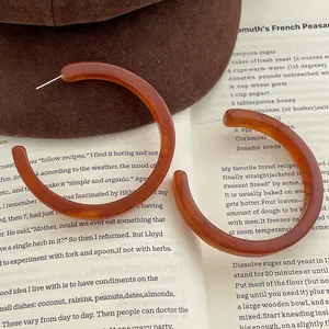 Vintage amber resin C-shaped hoop earrings displayed on a book and a felt hat