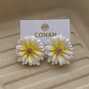 Gänseblümchen-Ohrstecker mit weißen Glitzerblättern und gelber Mitte auf Displaykarte