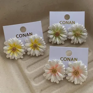 Detailliertes Set aus drei bunten Gänseblümchen-Ohrsteckern auf minimalistischer Karte