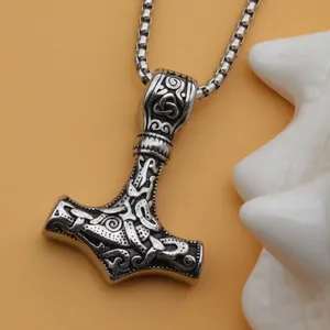 Gros plan du pendentif Mjölnir avec nœuds nordiques sur une chaîne à maillons carrés