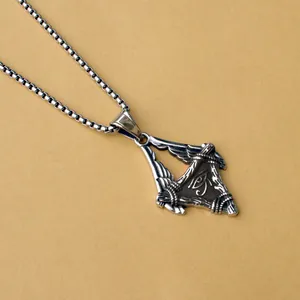 Macro detail of Eye of Horus pendant with silver wings on stainless steel box chain