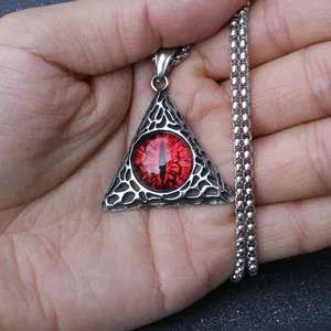 Détail d'un pendentif triangle argenté avec œil de dragon rouge et motifs en maille creuse