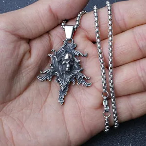 Detailed view of vintage silver skull pendant with baroque patterns held in hand