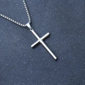 Polished silver stainless steel cross pendant with classic box chain on dark textured background