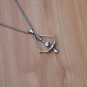 Detailed shot of polished stainless steel bow and arrow pendant with floral engraving