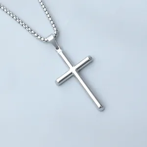 Close-up of a minimalist silver tubular cross pendant with a fine box chain necklace