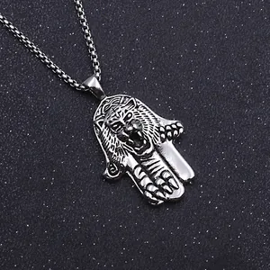 Macro detail of Hamsa Hand and tiger head pendant on a steel chain for men