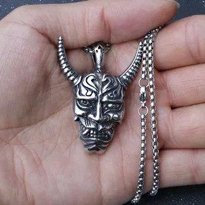 Detailansicht eines silbernen Hannya-Masken-Anhängers aus Edelstahl in der Hand
