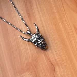 Nahaufnahme des Hannya-Maskenanhängers mit Vintage-Finish auf rustikalem Holzhintergrund