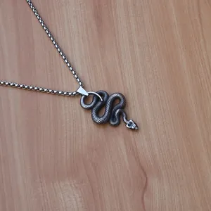 Detailed close-up of a vintage silver stainless steel snake pendant with scale textures