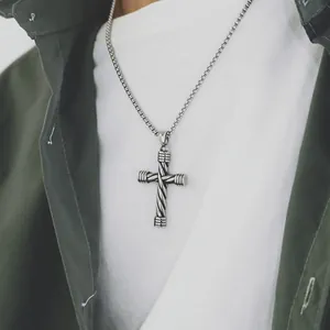 Detail of vintage silver cross necklace with twisted rope pattern on olive green shirt