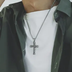 Detail of silver twisted texture cross pendant necklace worn by a male model
