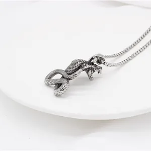 Macro shot of stainless steel cobra pendant with detailed scale texture on silver curb chain