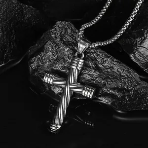Detail of cross pendant with twisted cable design and box chain on black rock