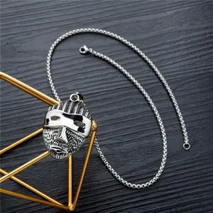 Retro tribal mask pendant necklace with polished silver finish on dark wood background