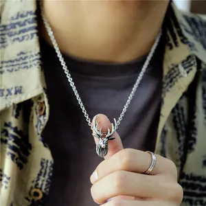 Detailed close-up of retro silver stag head pendant necklace on model's neck