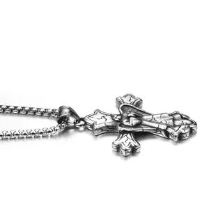 Détail macro du pendentif croix rétro en acier avec relief gothique et chaîne box