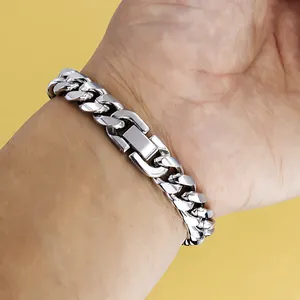 Close-up of a silver Cuban link bracelet with a wide fold-over clasp on a yellow background