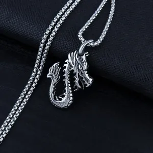 Close-up of a silver stainless steel dragon pendant with intricate scales on a box chain