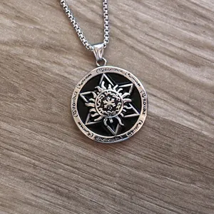 Detail of vintage silver sun and cross pendant on wood with a steel box chain