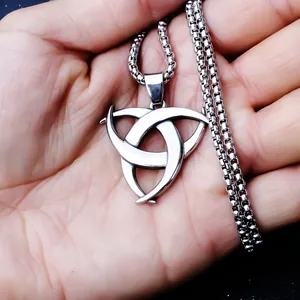 Dettaglio macro del ciondolo a nodo celtico Triquetra in argento tenuto in mano