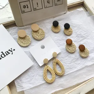 Detailed view of handmade woven rattan geometric drop earrings on a white aesthetic background