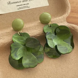 Detailed close-up of dark green floral earrings with marble texture petals and gold links