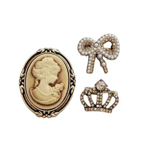 Vintage brooch set featuring a cameo lady, pearl bow, and sparkling crown in bronze finish