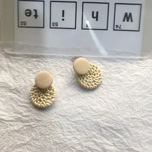 Macro detail of handmade rattan woven round earrings with matte top on textured paper