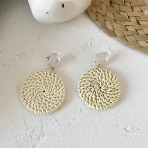 Detailed view of handmade cream rattan hoop earrings with white resin studs and spiral texture