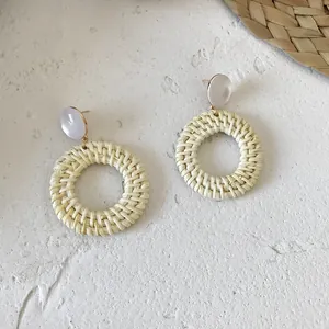 Close-up of handmade rattan hoop earrings with white round resin stud and gold connector