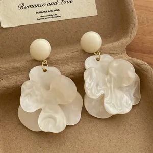 Detailed macro of vintage cream floral earrings with marble texture in a rustic gift box