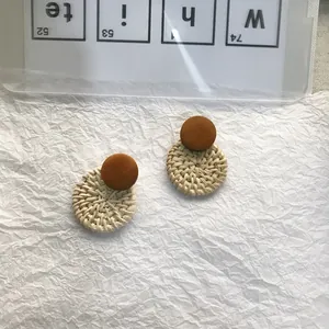 Detail of round rattan woven pendant and wooden stud on bohemian earrings