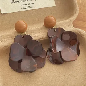 Detailed view of floral resin earrings with brown tortoiseshell texture and gold accents