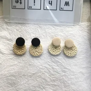 Detailed view of handmade woven rattan and wood geometric stud earrings in black and beige