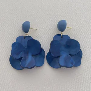 Detail view of deep blue floral earrings with marble texture and golden hardware