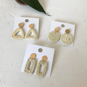 Detailed close-up of handmade geometric woven rattan earrings in triangle and circle shapes