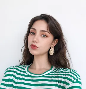 Close-up of model wearing boho round rattan and wood drop earrings with a natural finish